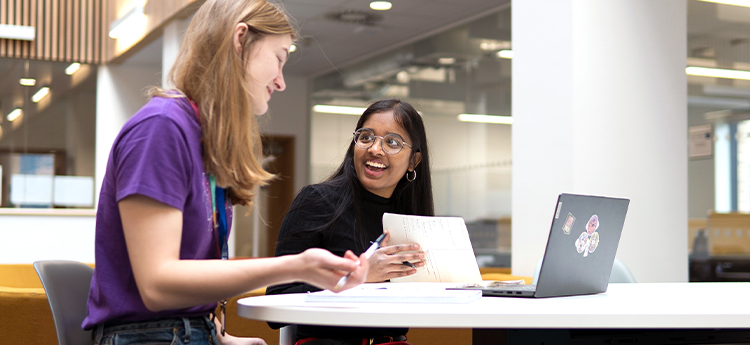 Two smiling students studying in the library