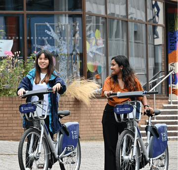 Students walking a Swansea University Cycles down the mall