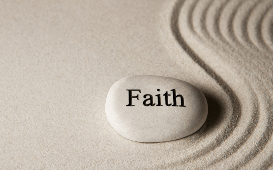A pebble with the word 'Faith' written on it, on stand with ripples.